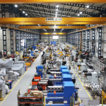 Intérieur d'une vaste usine avec des machines industrielles, des équipements et des allées bien éclairées.