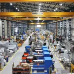 Intérieur d'une vaste usine avec des machines industrielles, des équipements et des allées bien éclairées.